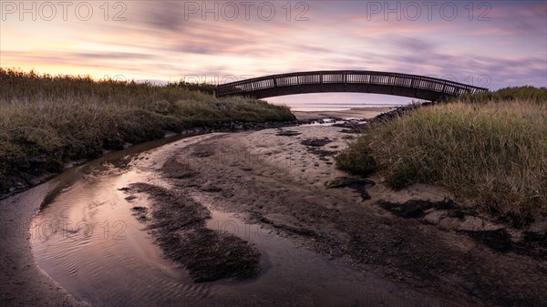 Colourful sunrise behind the Luegenbruecke on the mudflats in the east of the North Frisian island of Sylt