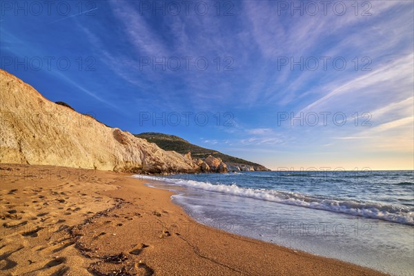 Beautiful low sun view of secluded and remote beach on sunny evening. High yellow cliffs