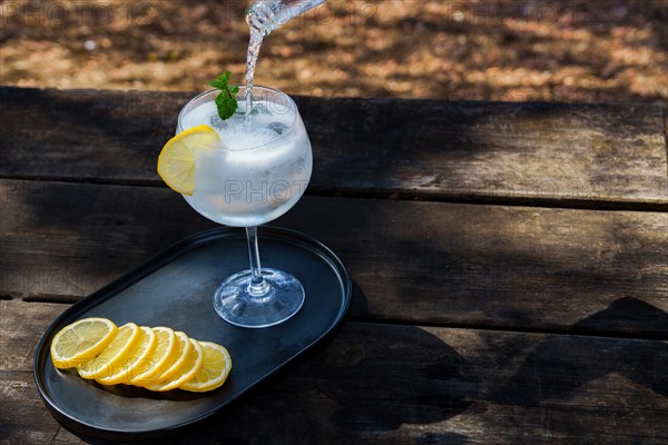 Top view of a bottle of tonic poured over a glass with ice