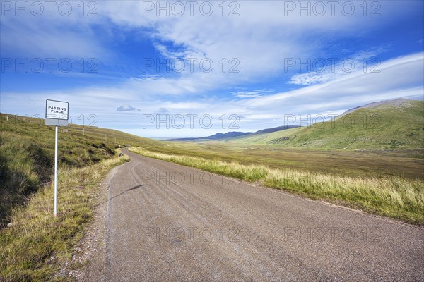 The single track road and tourist route or scenic road North Coast 500 also called NC500 with a passing place for oncoming traffic