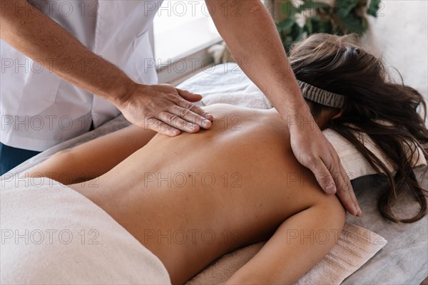 Portrait of a masseur treating the back woman lying on a stretcher on a clinic