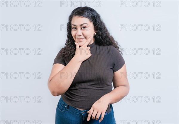 Beautiful latin girl thinking with hand on chin. Young woman rubbing chin with a doubtful expression