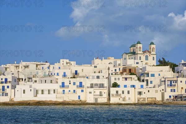 Traditional Greek whitewashed houses just by seafront on sunny day