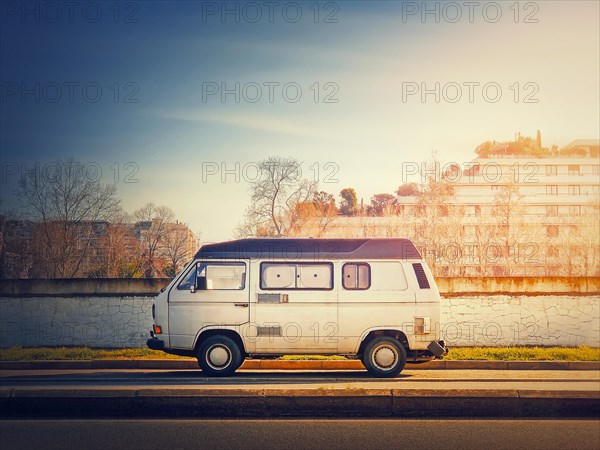 Old van parked on the edge of the street in the sunset sky background