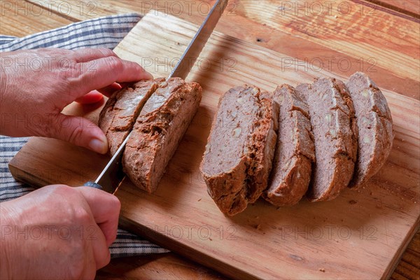 Woman cutting slices of rustic bread with a knife on a wooden board