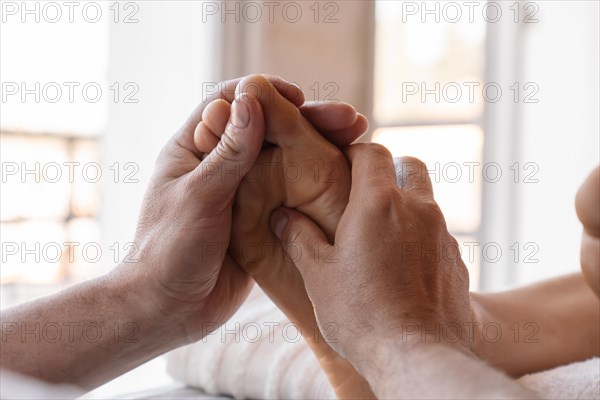 Foot reflexology massage. Male masseur performs acupressure on a woman's foot. Luminous background. Selective focus