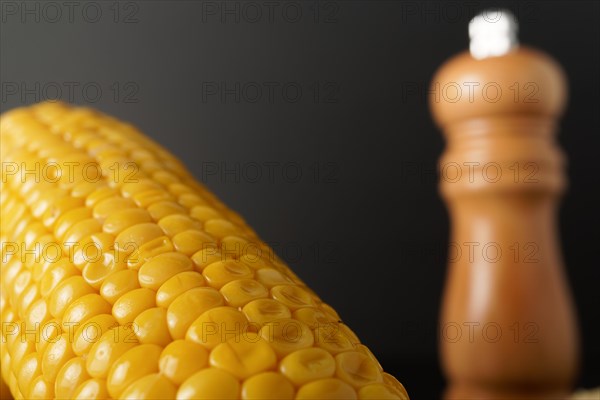 Corn cobs with pepper pot and spoon with butter