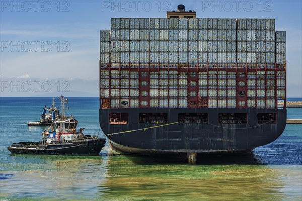 Container ship with tugboats in the harbour