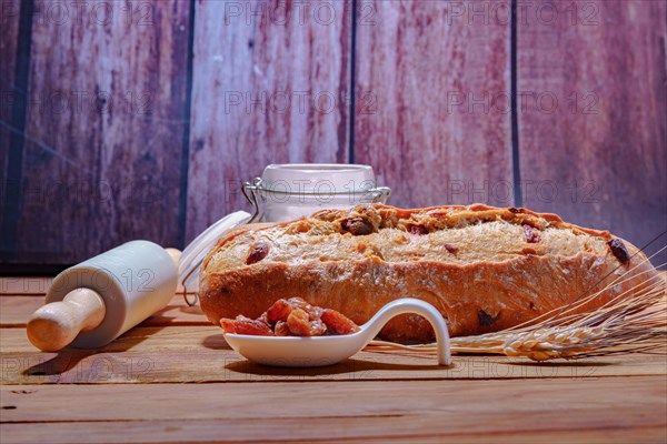 Loaf of rustic raisin bread on a wooden table with flour