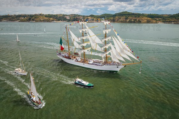 Aerial drone view of tall ships with sails sailing in Tagus river towards the Atlantic ocean in Lisbon