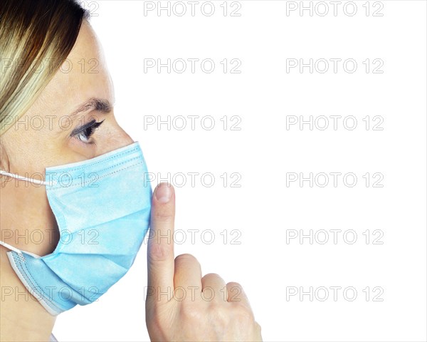 Woman wearing a face mask with her finger on her lips
