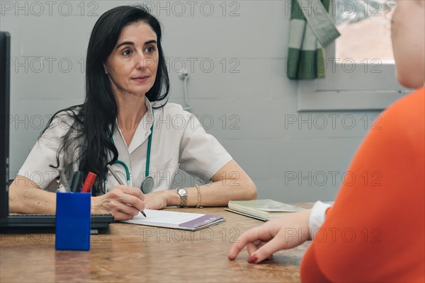 Woman doctor with stethoscope talking to patient in medical office