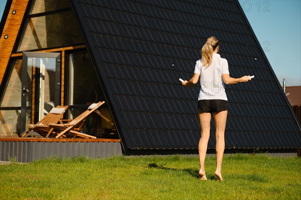 Unrecognizable woman jumps with a smart rope on the lawn next to log cabin