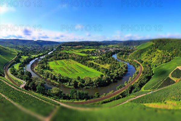 Wiltinger Saarbogen. The river winds through the valley and is surrounded by vineyards and green forests. Kanzem