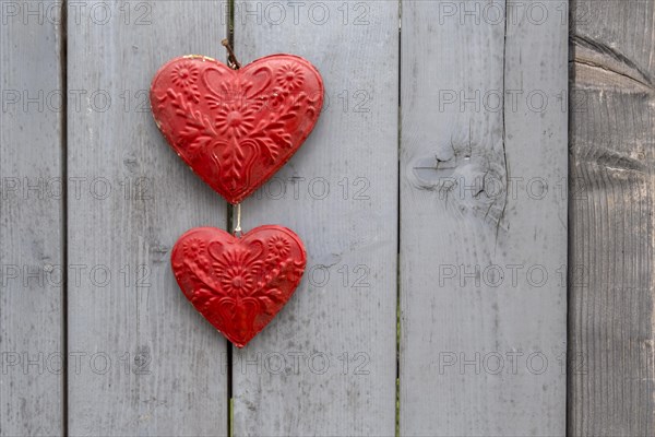 Two red metal hearts on a grey wooden gate