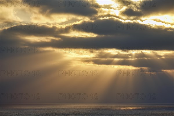 Sunbeams shining through clouds by the sea