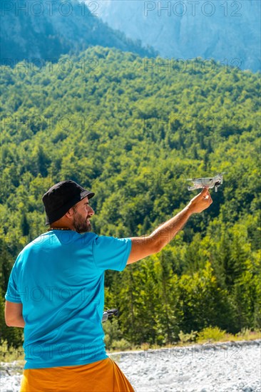 Drone pilot landing the drone in hand on the mountain in the Valbona natural park in summer. Albania