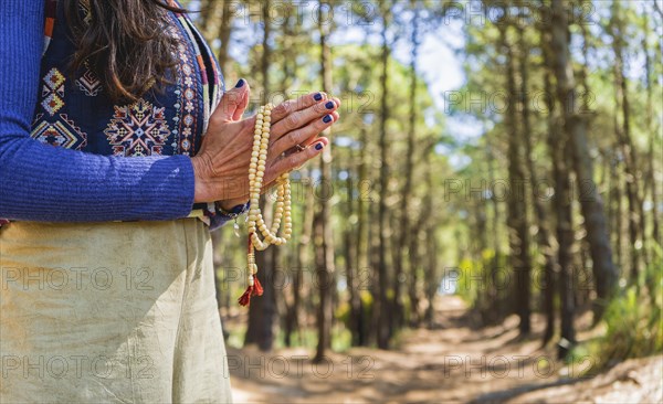 Close up of clasping hands holding a japa mala. Copy space