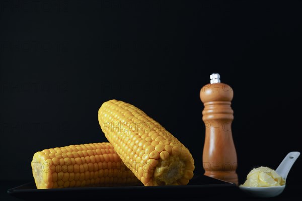 Corn cobs with pepper pot and spoon with butter