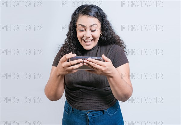 Happy latin girl using cell phone on isolated background. Cheerful people looking at a promotion on the phone isolated
