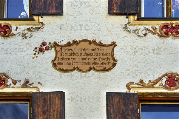 Restored old building facade with painted window decorations and motto by Goethe