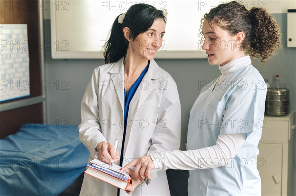 Doctor with medical student explaining treatment both in hospital uniform