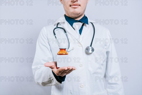 Doctor hand holding a bottle of syrup. Doctor showing a bottle of syrup