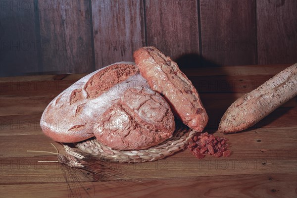 Loaf and loaves of rustic bread with ears of wheat on wooden table