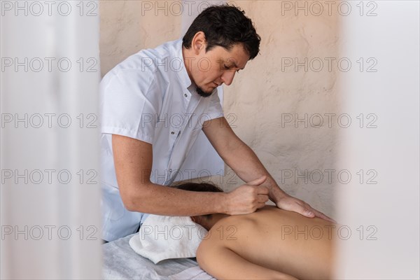 Professional male masseur therapist performs therapeutic body massage for young woman. Massage treatment for stress relief