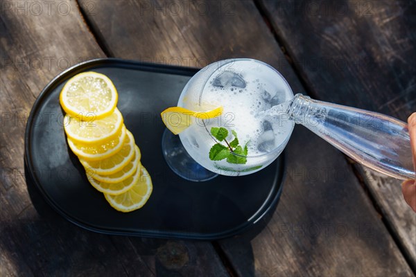 Top view of a bottle of tonic poured over a glass with ice