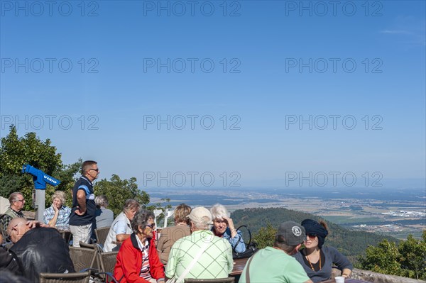 Tourists at the viewpoint in front of the Chateau du Haut Koenigsbourg. In the background the Upper Rhine Plain and the hilly landscape of the Black Forest