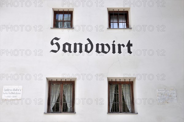 Facade and commemorative plaque of the historic Sandwirt inn in the Passeier Valley