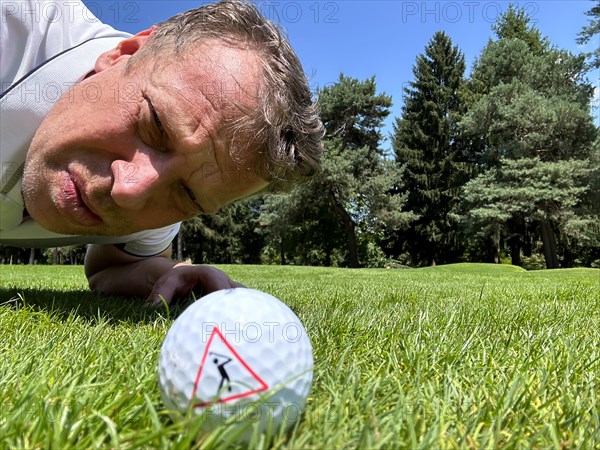 Golfer Looking at a Golf Ball with Warning Sign on the Fairway in a Sunny Day in Switzerland