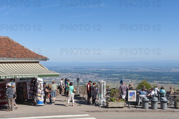 Tourists at the viewpoint in front of the Chateau du Haut Koenigsbourg. In the background the Upper Rhine Plain and the hilly landscape of the Black Forest