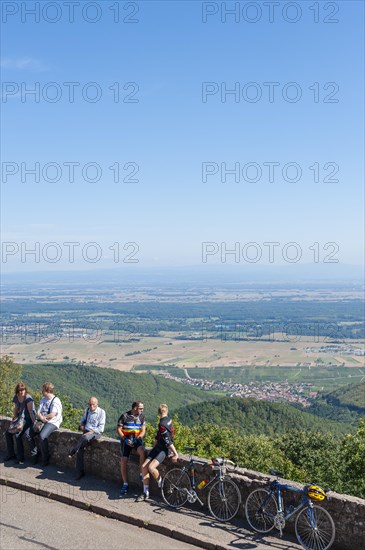 Tourists at the viewpoint in front of the Chateau du Haut Koenigsbourg. In the background the Upper Rhine Plain and the hilly landscape of the Black Forest