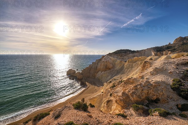 Beautiful low sun view of secluded and remote beach on sunny evening. High yellow cliffs