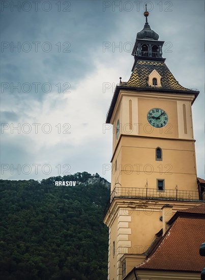 The council house clock tower with a beautiful view to the Brasov sign on top of the hill. Popular tourist location in Romania
