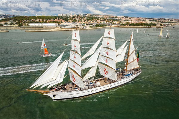 Aerial drone view of tall ships with sails sailing in Tagus river towards the Atlantic ocean in Lisbon