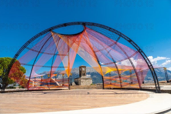 Colored arch in the Ottoman Castle Fortress of Gjirokaster or Gjirokastra and in the background the church with the clock tower. Albania