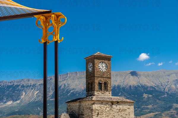 Colored arches in the Ottoman Castle Fortress of Gjirokaster or Gjirokastra and in the background the church with the clock tower. Albania