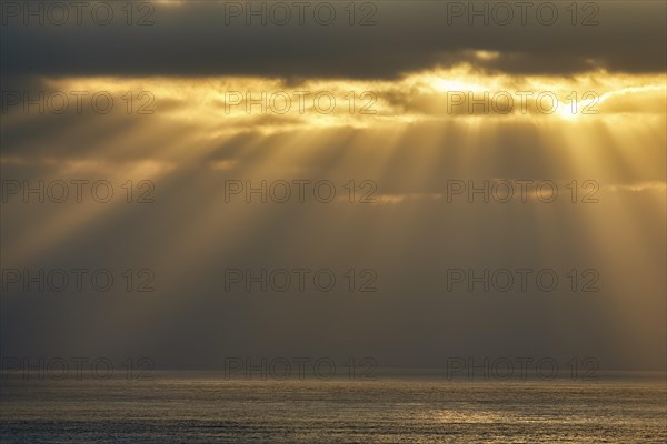 Sunbeams shining through clouds by the sea