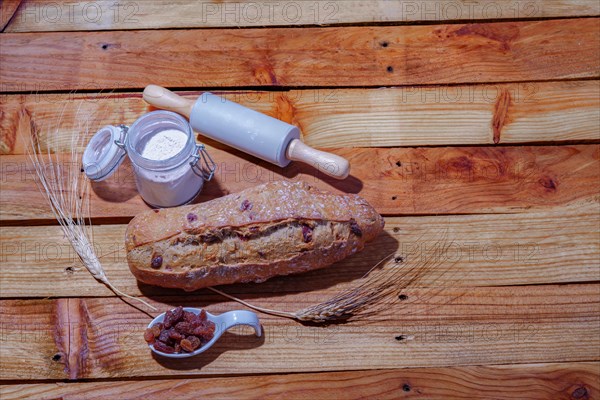 Loaf of rustic raisin bread on a wooden table with flour