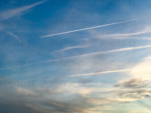 Sky shortly in front of dusk with veil clouds cirrostratus and contrails from air traffic