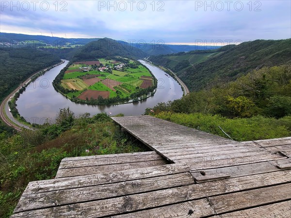 River bend of the Saar. The river winds through the valley and is surrounded by green hills and forests. Serrig