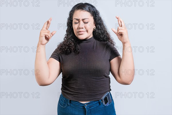 Latin girl crossing fingers making a wish. Smiling young woman making a wish with hopeful gesture