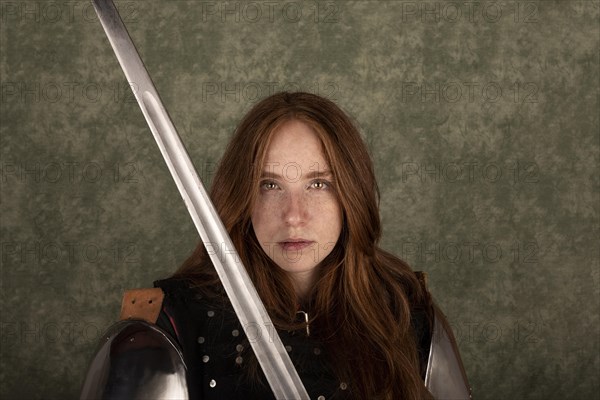 History of the Middle Ages. Portrait of a beautiful medieval female knight in armour on a green background