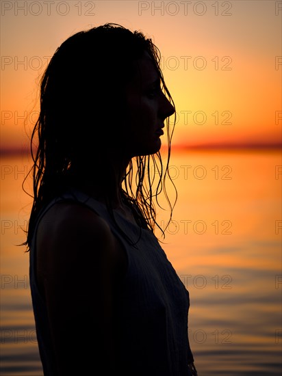 Silhouette of a young woman in the water at dusk