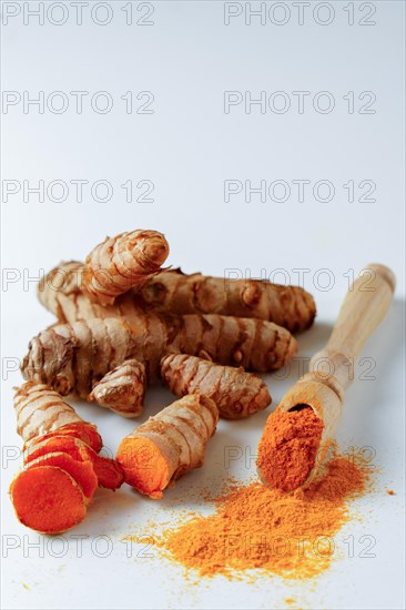 Fresh turmeric root and ground turmeric on a wooden spoon isolated on white background and copy space