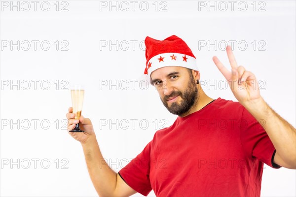 Young very happy Caucasian man with red Christmas hat toasting with a glass of champagne on a white background