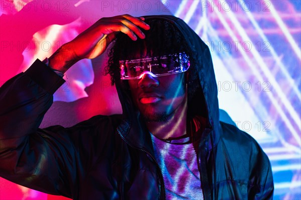 Studio portrait with purple and blue neon lights of a cool futuristic man with artificial intelligence goggles